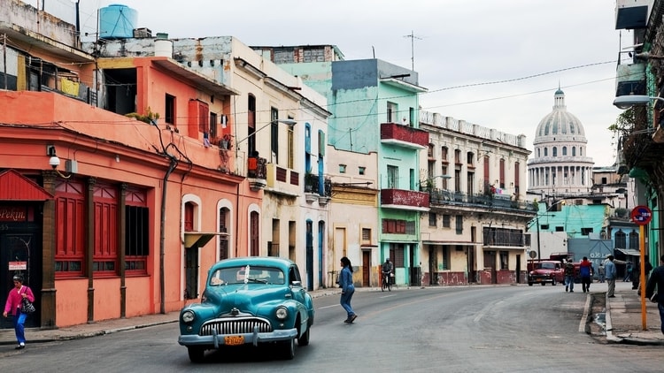 A vintage car driving in the streets of Havana, Cuba which is one of the cheapest travel destinations in the Caribbean for budget travelers