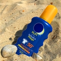 A bottle of sunscreen displayed next to other beach accessories by a traveler on vacation