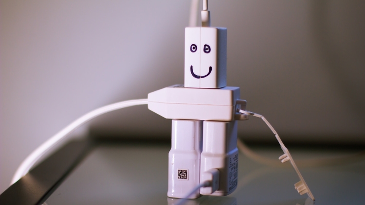 Travel adapters and chargers arranged to display a smiling figure